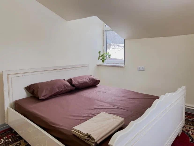 Un dormitorio con una cama con sábanas moradas y una ventana en Sargsyans guest hause, en Bjni