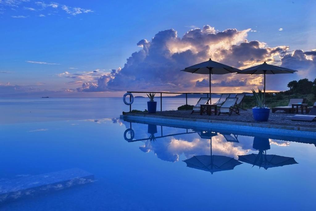 - une piscine avec chaises longues, parasols et eau dans l'établissement Le Grand Bleu, à Andilana