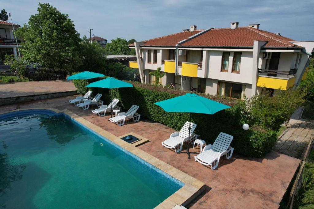 einen Pool mit Stühlen und Sonnenschirmen neben einem Haus in der Unterkunft Indigo Villas in Pismenovo
