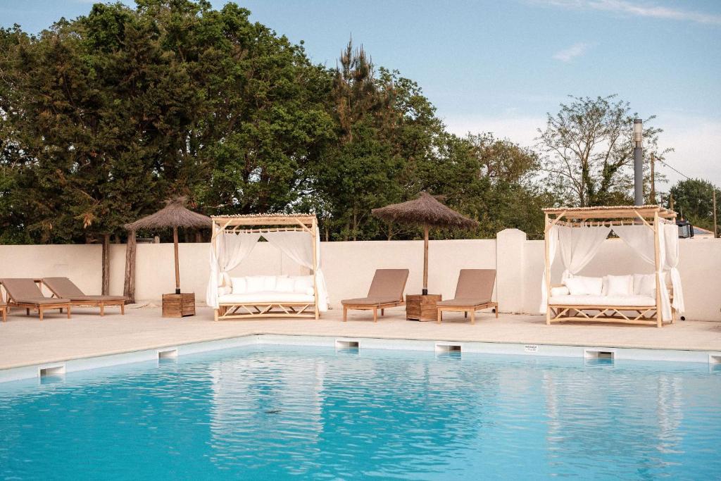 una piscina con sillas y sombrillas junto a una piscina en INSPIRE Villages - Marennes Oléron en Marennes