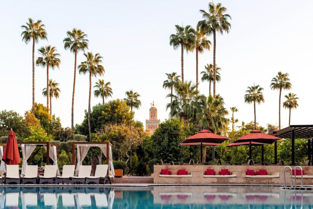 een zwembad met stoelen, parasols en palmbomen bij TUI BLUE Medina Gardens - Adults Only - All Inclusive in Marrakesh
