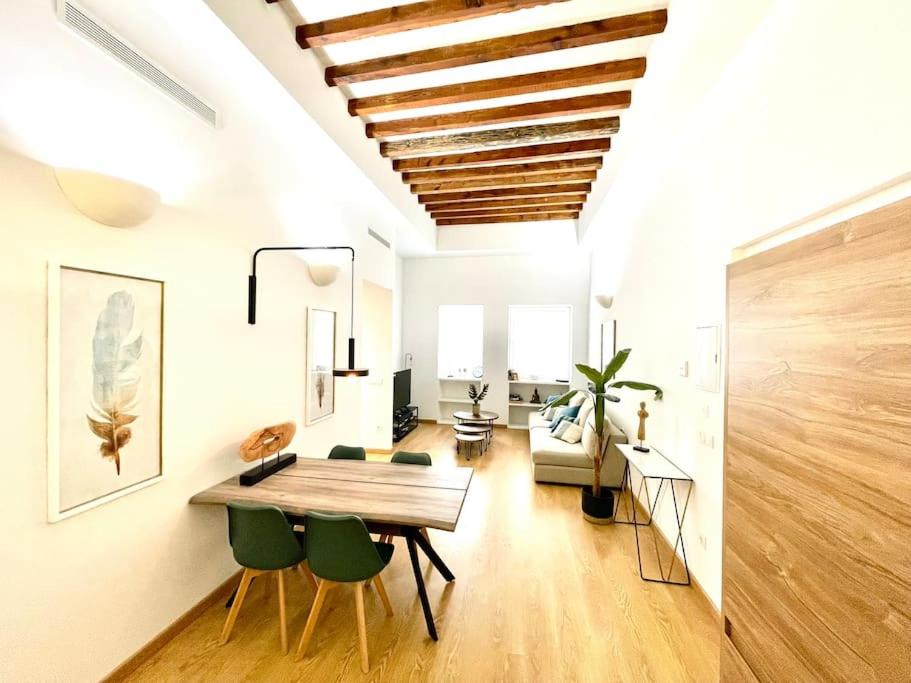 sala de estar con mesa de madera y sillas verdes en Apartamento playa del Postiguet en Alicante