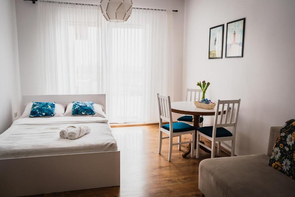 a bedroom with a bed and a table with a chair at Apartamenty Baltyckie in Władysławowo