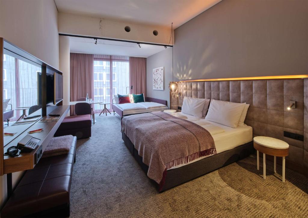 ein Hotelzimmer mit einem großen Bett und einem Schreibtisch in der Unterkunft Adina Apartment Hotel Nuremberg in Nürnberg