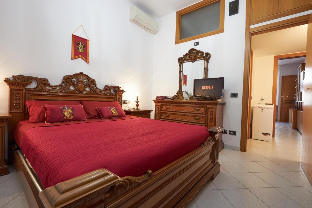 a bedroom with a large bed with red sheets and a television at Harry Potter's Magic House - Metro M4 - Linate - Città Studi in Milan