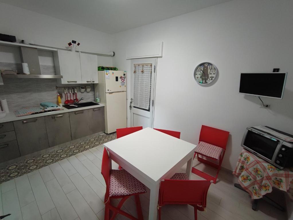 a kitchen with a white table and red chairs at B&b Casa Vita COMFORT HOME in Marconia