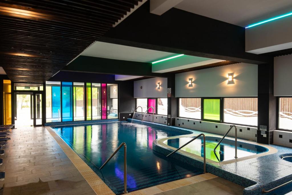 a large swimming pool in a building with windows at Altus Hotel & Spa in Praid