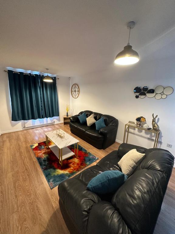 a living room with a leather couch and a table at Trinity's Place in Wythenshawe