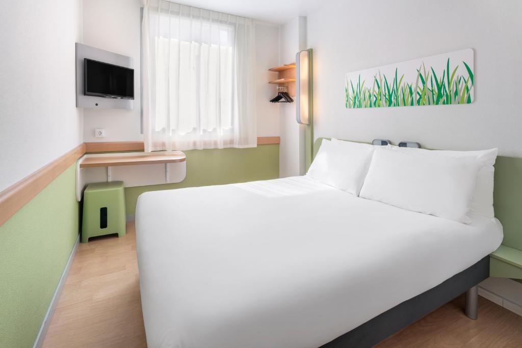 a bedroom with a white bed and a tv at B&B HOTEL Zaragoza Plaza Mozart in Zaragoza