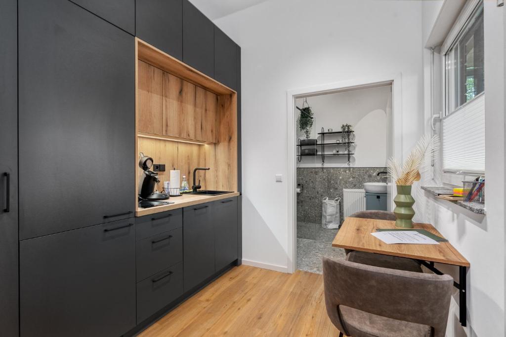 eine Küche mit schwarzen Schränken und einem Holztisch in der Unterkunft Apartment klein aber fein in Friedrichshafen in Friedrichshafen