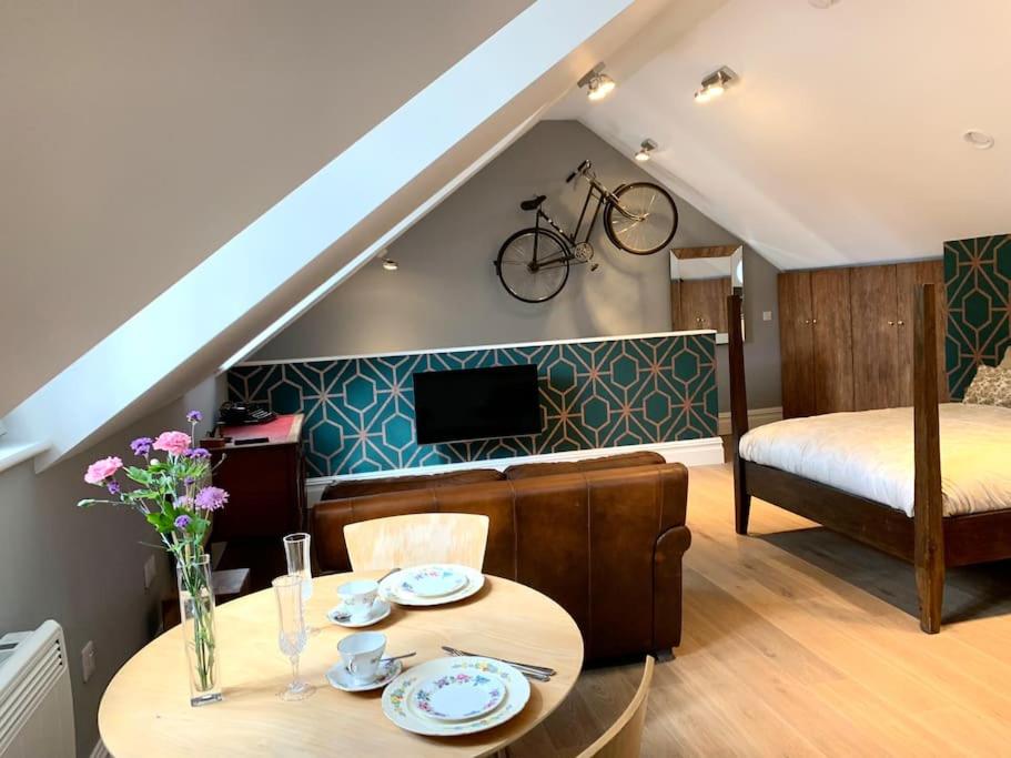 ein Wohnzimmer mit einem Tisch und einem Fahrrad an der Wand in der Unterkunft Scholar's Loft - Cosy & Close to Central Cambridge in Cambridge