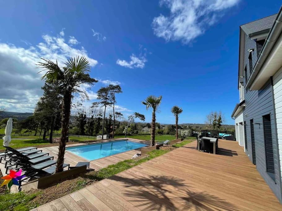 a backyard with a swimming pool and a wooden deck at Villa avec piscine, vue mer et campagne. in Bonneville-sur-Touques