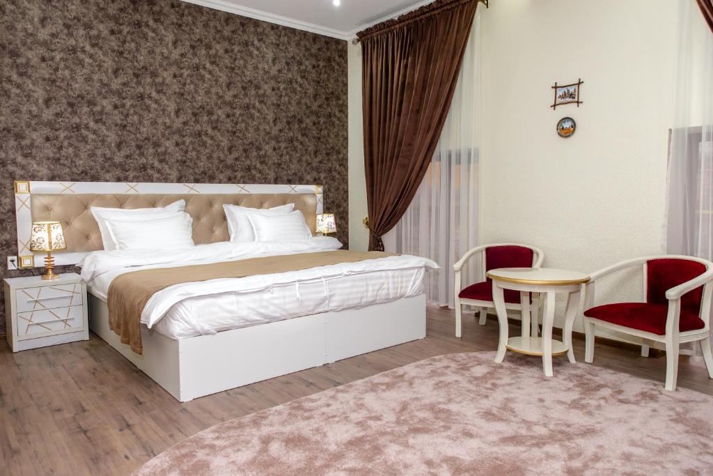 sypialnia z łóżkiem, stołem i krzesłami w obiekcie The Royal Hotel w Samarkandzie