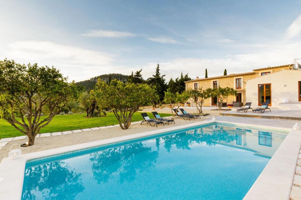 a pool with chairs and a house in the background at Can Tortet in Pollença