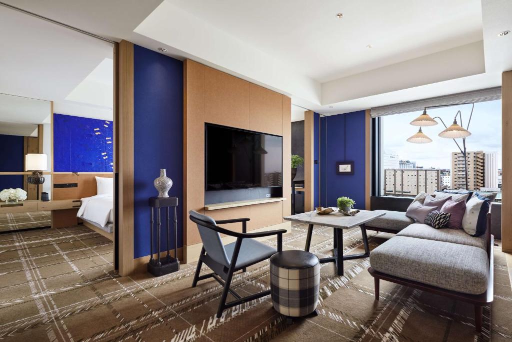 a living room with a couch and a table and a tv at Hyatt Centric Kanazawa in Kanazawa