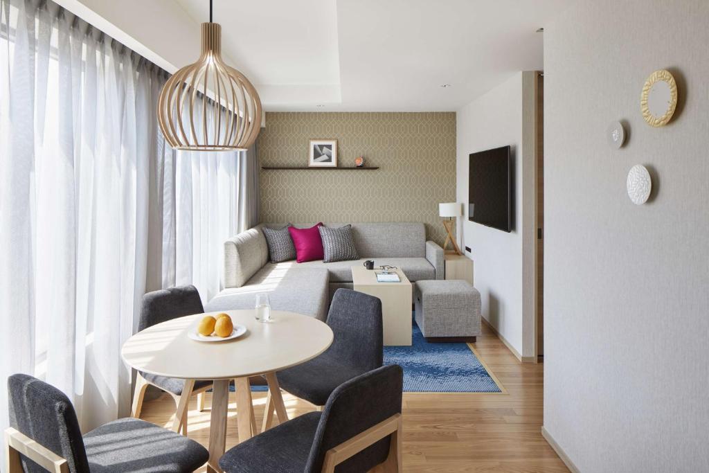 a living room with a couch and a table and chairs at Hyatt House Kanazawa in Kanazawa