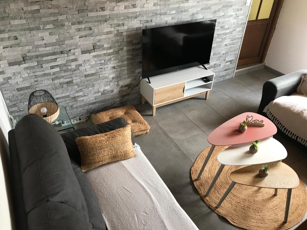 a living room with a couch and tables and a tv at Maison avec spa - Côte d'Opale in Lottinghen