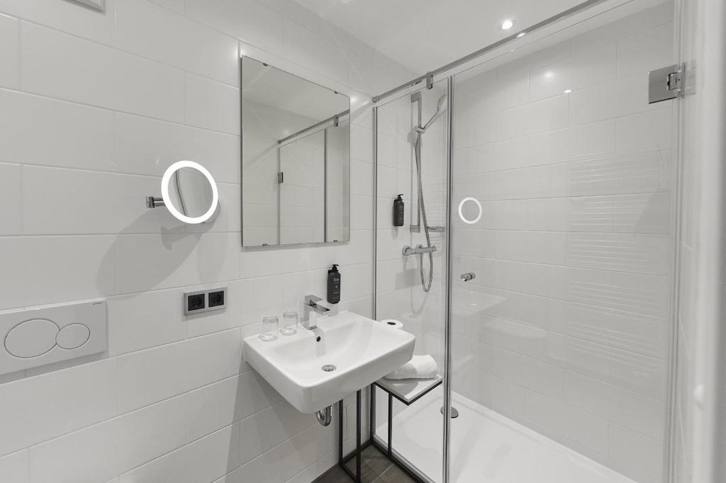 a white bathroom with a sink and a shower at Hotel Rhönkitz in Bad Kissingen
