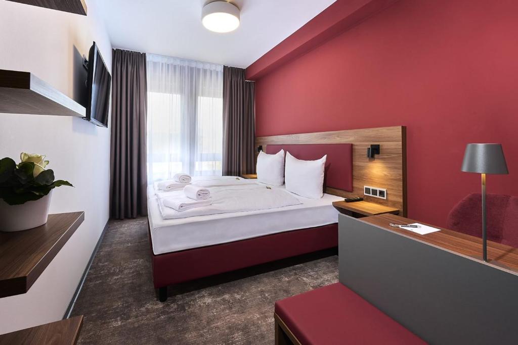 a bedroom with a large bed with a red wall at Hotel Rhönkitz in Bad Kissingen