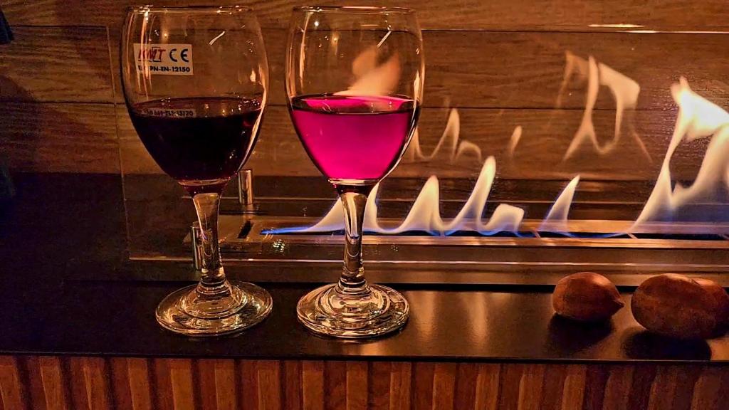 dos copas de vino en una mesa con chimenea en Casa Nov Complex, en Nov