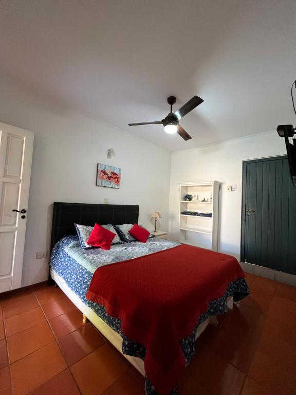 una camera da letto con letto con cuscini rossi e ventilatore a soffitto di Patry's Cottage a Puerto Iguazú