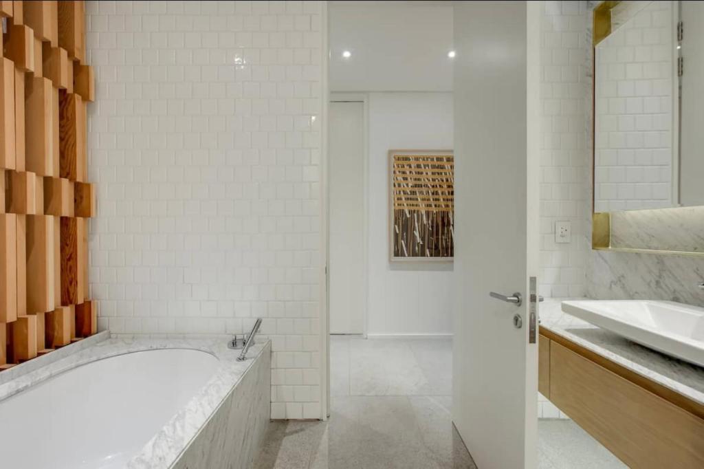 Baño blanco con bañera y lavamanos en Blair Atholl Estate, en Lanseria