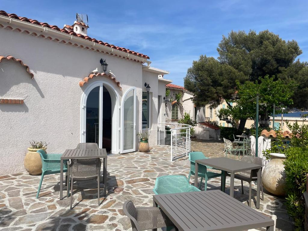 eine Terrasse mit Tischen und Stühlen vor einem Haus in der Unterkunft Hôtel Astria in Le Lavandou