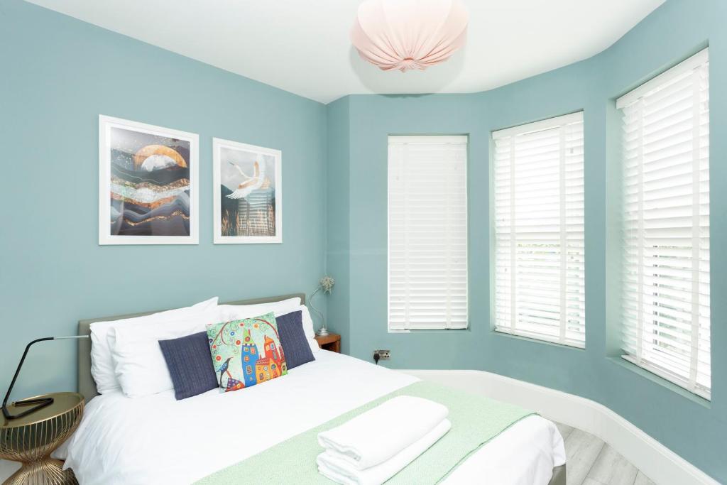 a bedroom with blue walls and a bed and windows at Sundance Cosy Getaway - Annexe in Whitstable