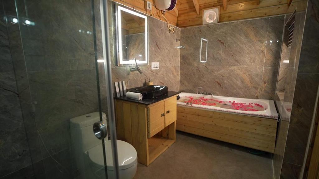 a bathroom with a tub and a toilet and a sink at DSR Wooden Cottages in Hyderabad