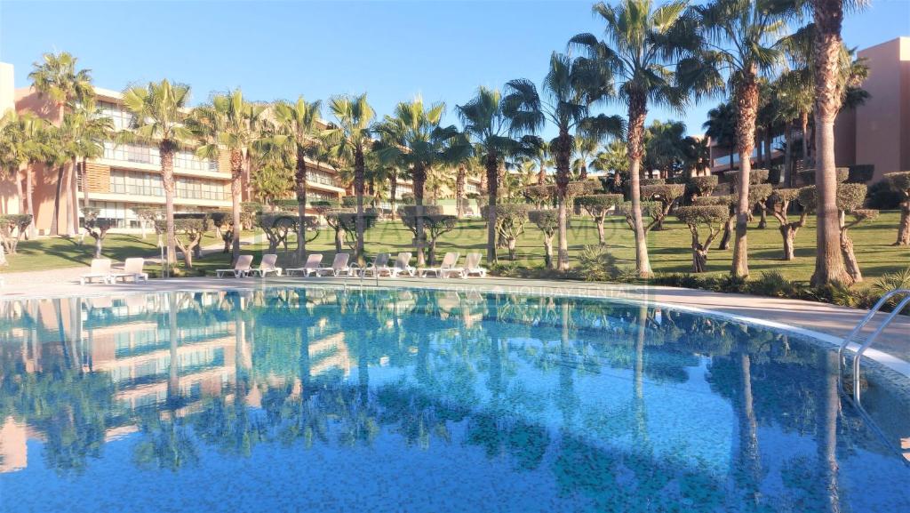 una grande piscina con palme sullo sfondo di Apartamento T2 Salgados ad Albufeira