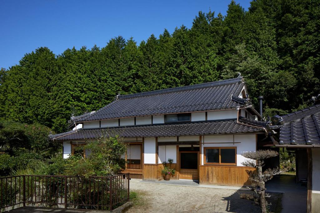 une maison avec un toit noir et blanc dans l'établissement Casa KitsuneAna The Satoyama experience in a Japanese-style modernized 100-year-old farmhouse, à Akaiwa