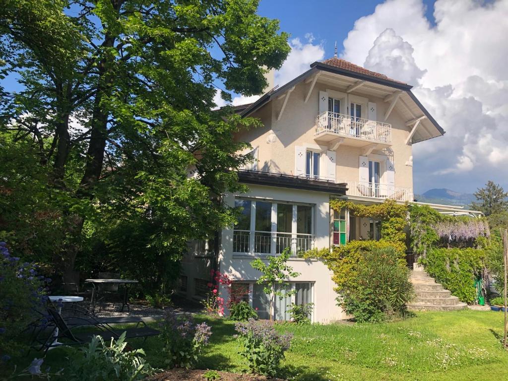 een groot wit huis met een balkon op een tuin bij Les Cyprès in Vevey