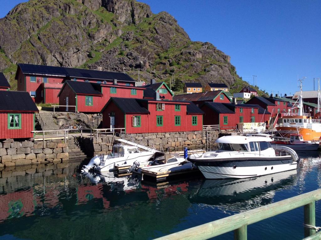 a group of boats docked in a harbor with red buildings at Autentisk rorbu i burekka, Stamsund in Stamsund