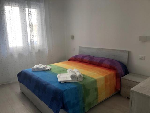 een slaapkamer met een regenboogbed en handdoeken. bij Casa Estiva Francesco e Nicolò in Vieste
