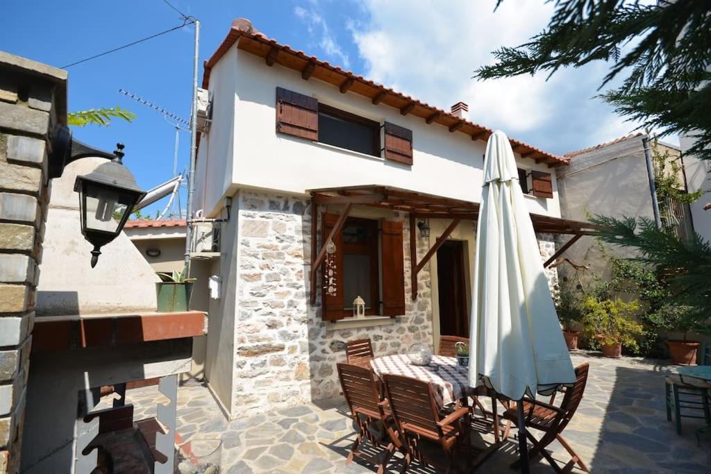 a patio with an umbrella and a house at Two-storey house with loft at Agria,Volos in Agria