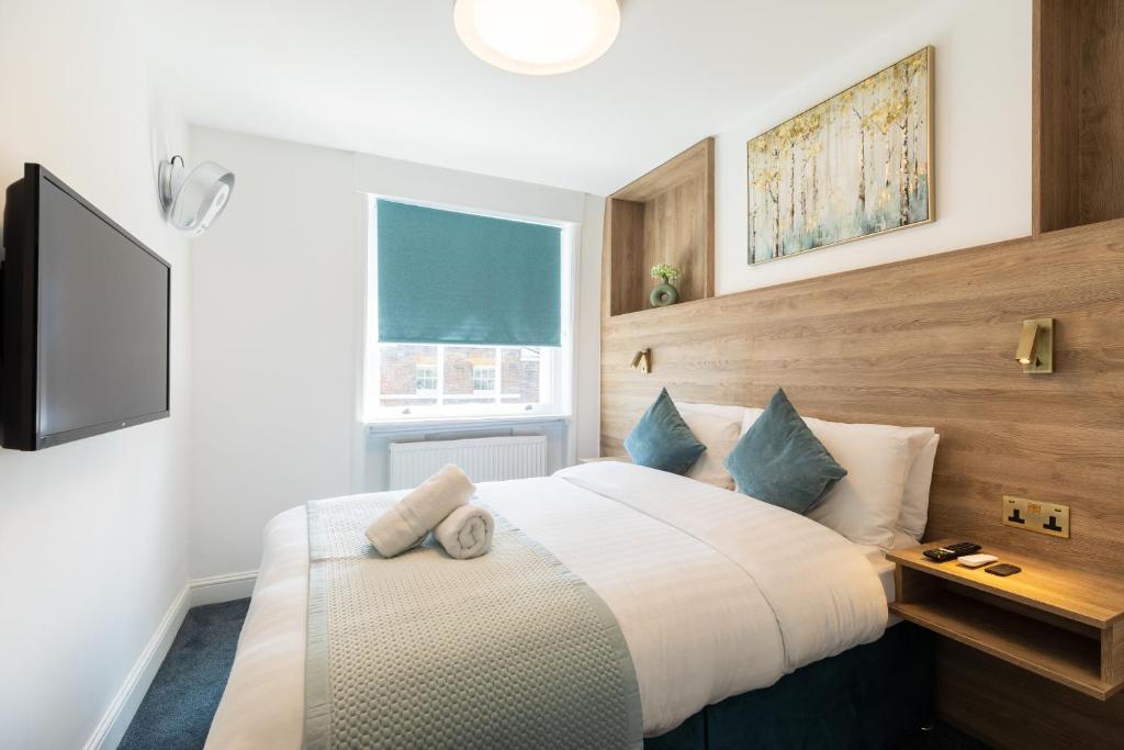 un dormitorio con una cama grande blanca con almohadas azules en Griffin House Hotel, en Londres