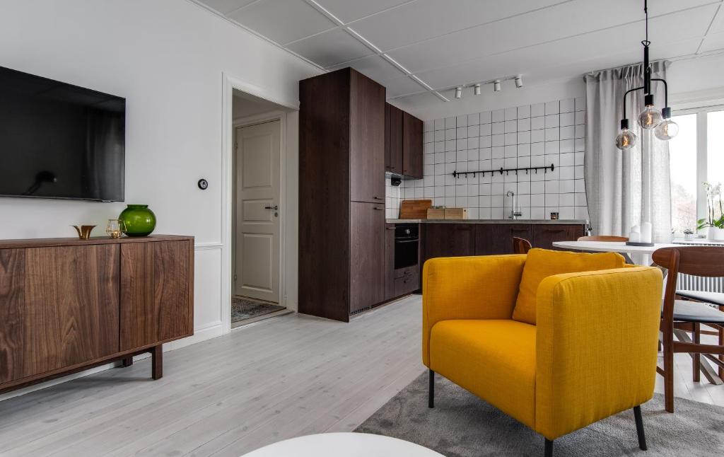 a living room with a yellow chair and a kitchen at Luxurious apartment for the modern executive in Luleå