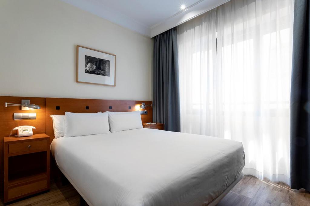 Un dormitorio con una gran cama blanca y una ventana en Petit Palace Cliper-Gran Vía, en Madrid