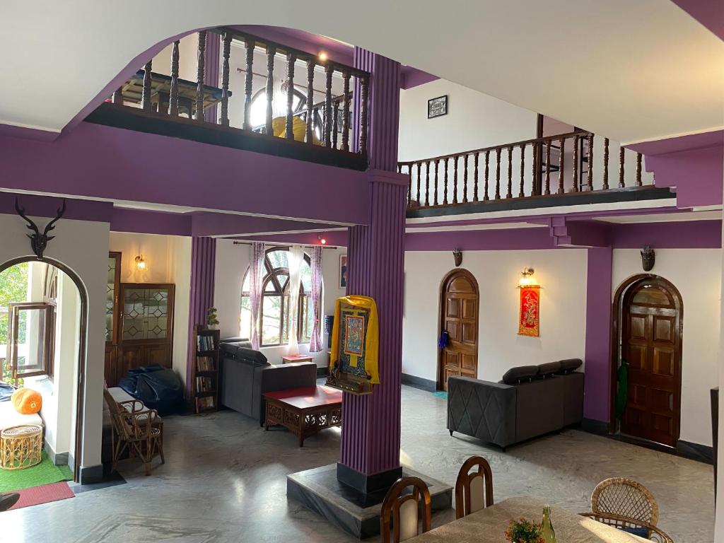 una sala de estar con paredes de color púrpura y una habitación grande con en Tashila Hostel en Gangtok