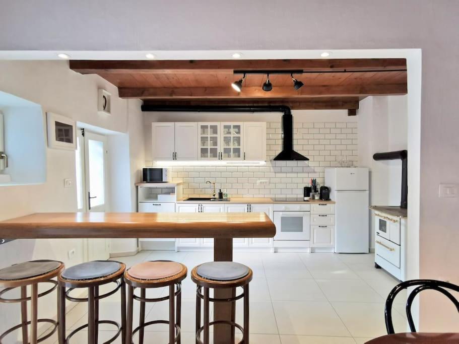 a kitchen with a large wooden table and stools at Smetova - The Blue Door House in Šempas