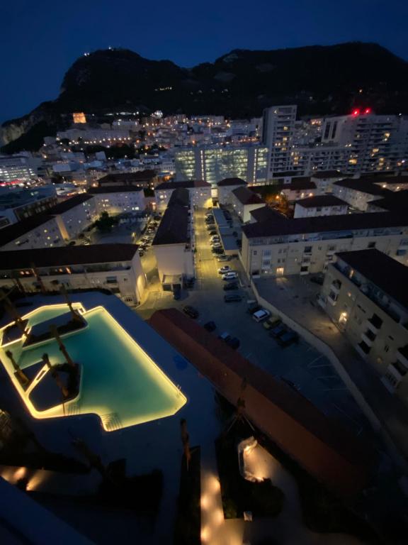 uma vista para uma cidade à noite com uma piscina em Ardwyn Studio Apartments Gibraltar em Gibraltar