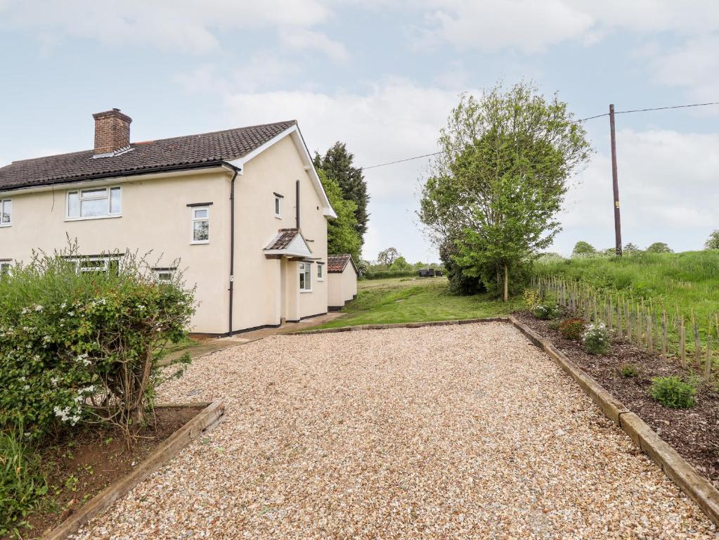 a white house with a gravel driveway at 6 Hillside Cottages in Gainsborough