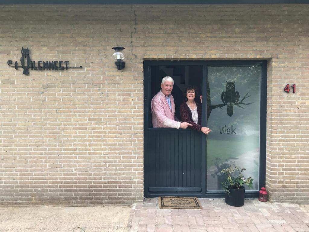 um homem e uma mulher à porta em Het Uilennest em Exloo