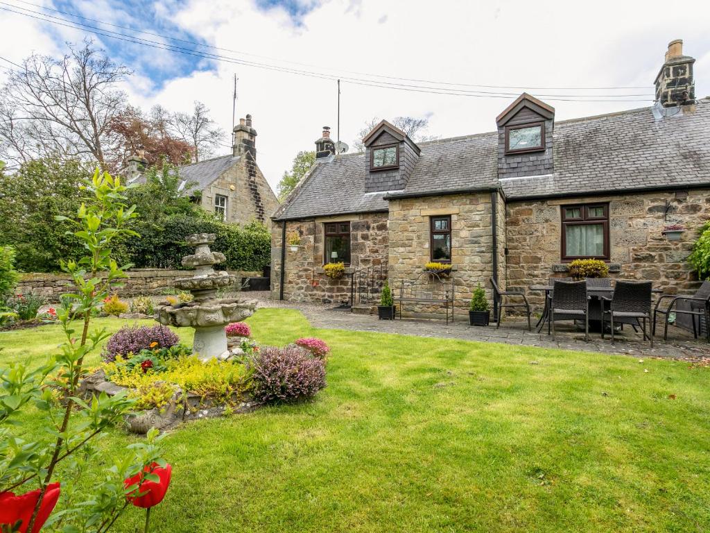 an old stone house with a garden in front of it at Aryarch in Eglingham