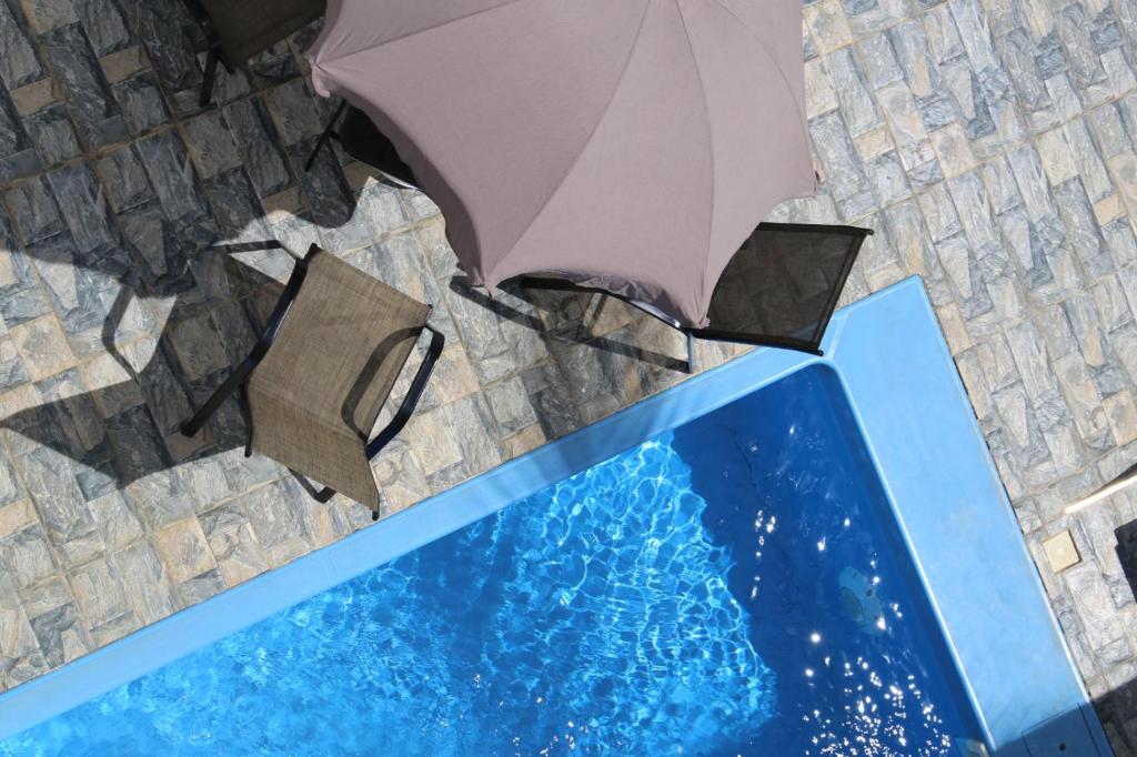 an umbrella sitting on top of a table next to a swimming pool at 3 Bedroom Family Pool Villa Flic-en-Flac Beach in Flic-en-Flac