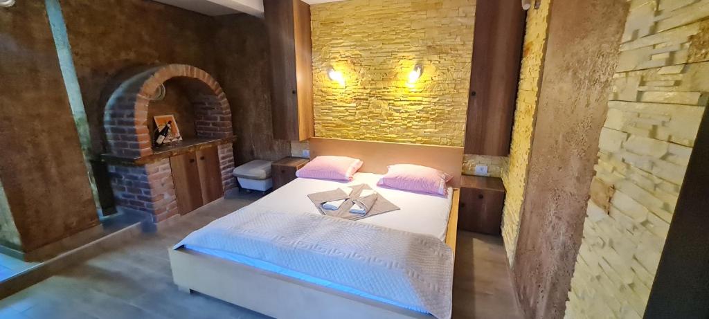 a bedroom with a bed and a brick wall at Apartments Lukić in Soko Banja