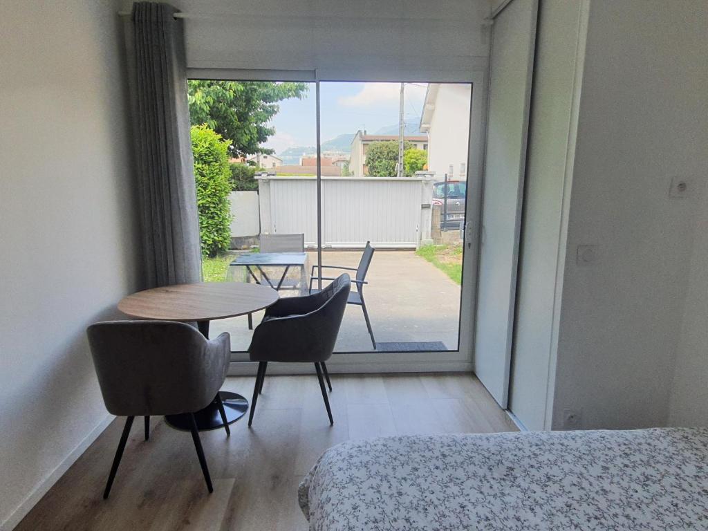 une chambre avec une table, des chaises et une fenêtre dans l'établissement Studio calme dans villa habitée, parking disponible et sûr, à Rhut