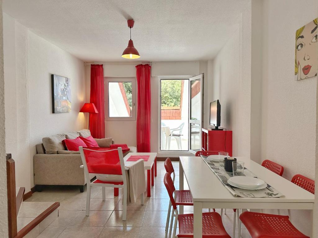 ein Wohnzimmer mit einem Tisch und roten Stühlen in der Unterkunft El Encinar de Apartamentos Cantabria in Isla
