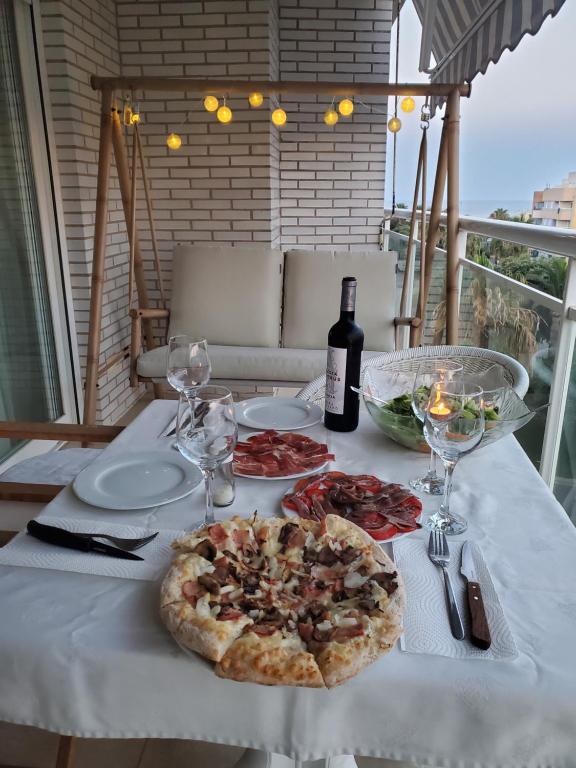 einen Tisch mit einer Pizza und einer Flasche Wein in der Unterkunft Apartamento en la Playa Benicarló Peñíscola in Benicarló