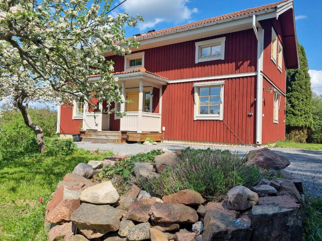 una casa roja con rocas delante de ella en Sällinge House - Cozy Villa with Fireplace and Garden close to Uppsala, en Uppsala